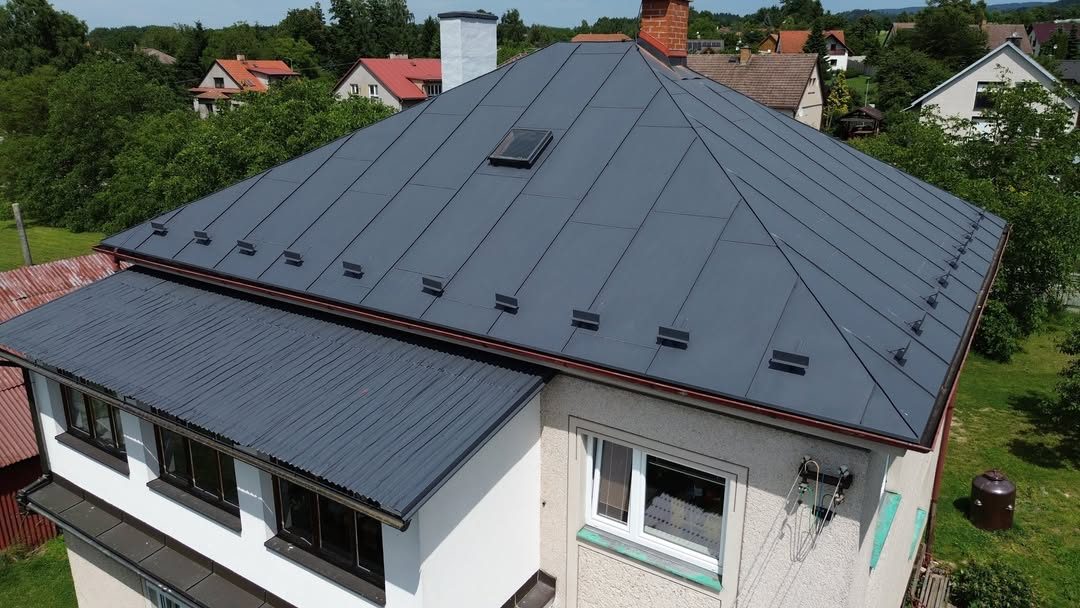 Rodinný dům s nově natřenou tmavou plechovou střechou, záběr z dronu